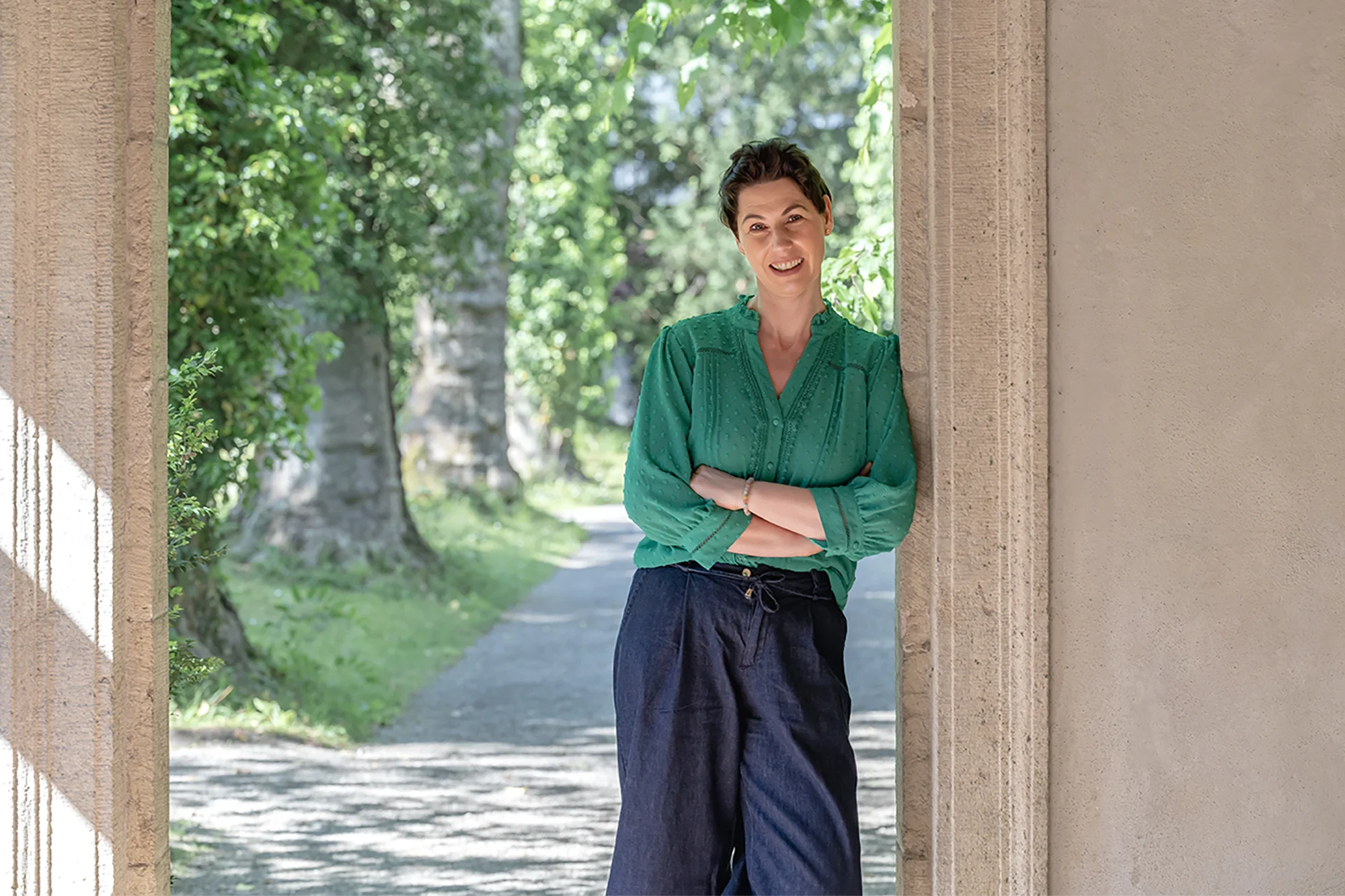 Nadine Devaux, die das Mentoring durchführt, lehnt sich in einem Park an eine Wand an.